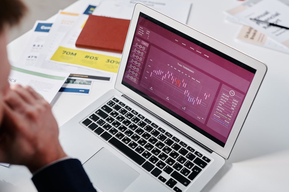 Businessperson reviewing data analytics on a laptop screen in an office setting.
