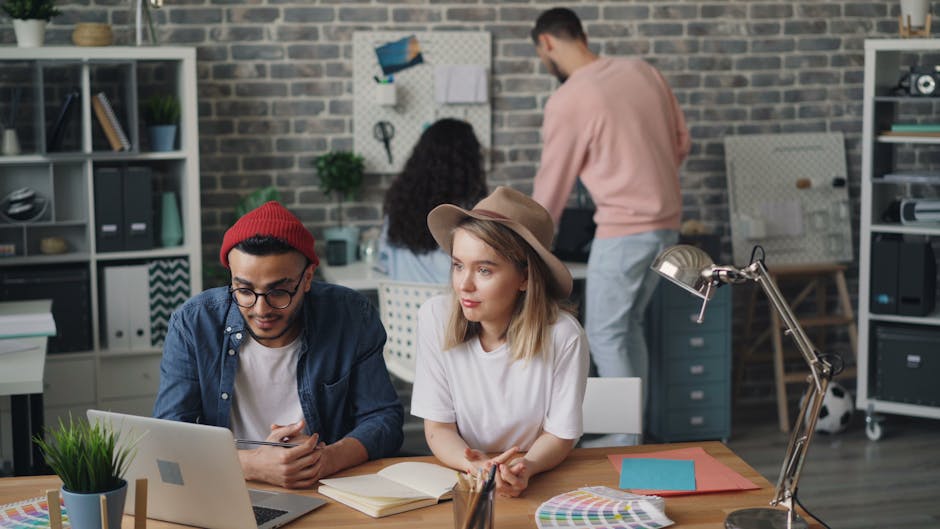 Young professionals collaborating on a project in a trendy office setting, with laptops and creative tools.